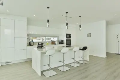 a kitchen with white walls and a counter with stools at Villa Noelia Ocean View in Prazeres