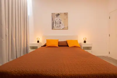 a bedroom with a large bed with two orange pillows at VIP Baía Beach in Machico