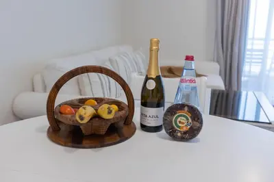 a basket of fruit and a bottle of wine on a table at Formosa Beach Apartment Vista Mar a 2 Minutos da Praia in Funchal