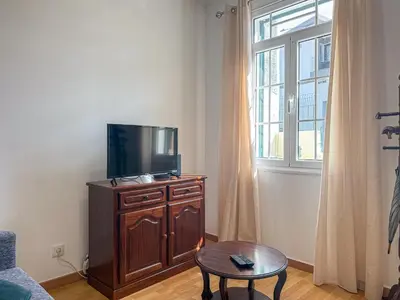 a living room with a tv on a dresser with a window at Funchal Bartolomeu Explorers in Funchal