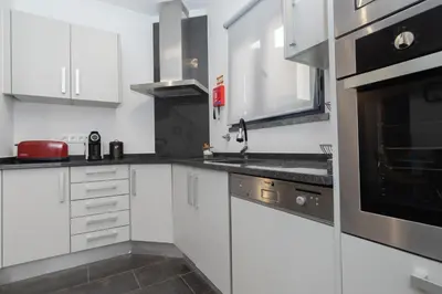 a kitchen with white cabinets and black appliances at Vila Margot by Rent-a-key in Caniço