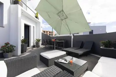 a patio with a table and an umbrella on a balcony at Vila Margot by Rent-a-key in Caniço