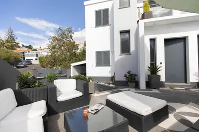 a balcony with white furniture and a white house at Vila Margot by Rent-a-key in Caniço
