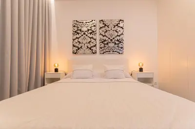a bedroom with a large white bed with two lamps at VIP Baía Beach B in Machico