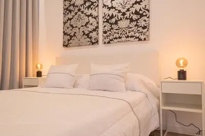 a bedroom with a white bed with two lamps at VIP Baía Beach B in Machico