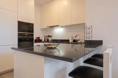 a kitchen with a black counter top and white cabinets at VIP Baía Beach B in Machico