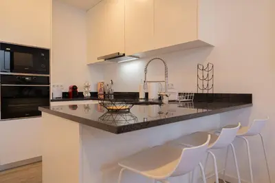a kitchen with a counter with stools around it at VIP Baía Beach C in Machico