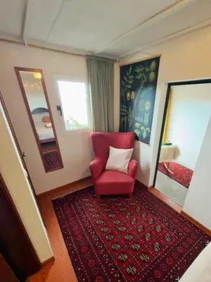 a living room with a red chair and a red rug at Casa Vintage Seixal Madeira in Seixal