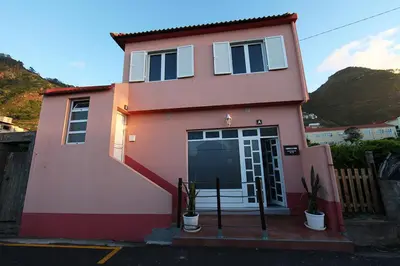 a pink house with a large door in front at Campo & Mar Apartments in Porto Moniz