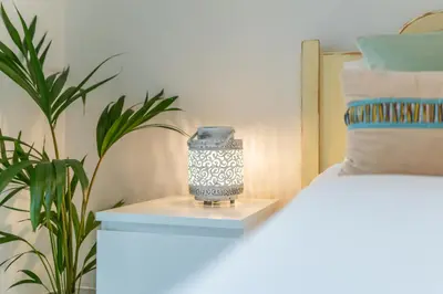 a vase sitting on a table next to a bed at Campo & Mar Apartments in Porto Moniz