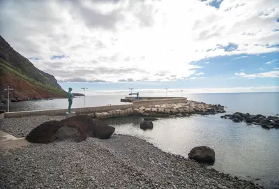a man standing on a pier next to the water at Wave Shadows Beach House Oceanfront property - Top Floor in Paul do Mar