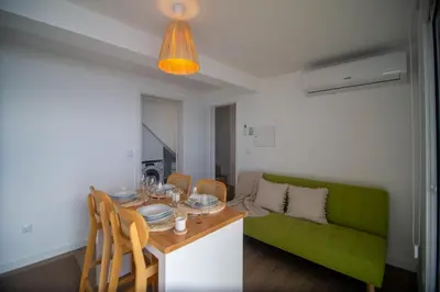 a living room with a table and a green couch at Wave Shadows Beach House Oceanfront property - Top Floor in Paul do Mar