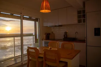a kitchen with a table and chairs and a view of the ocean at Wave Shadows Beach House Oceanfront property - Top Floor in Paul do Mar