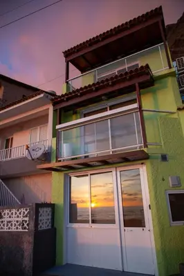 a house with a sunset seen through the windows at Wave Shadows Beach House Oceanfront property - Top Floor in Paul do Mar