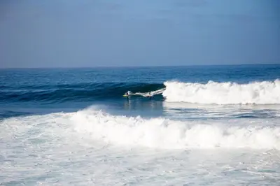 a person riding a wave on a surfboard in the ocean at Wave Shadows Beach House Oceanfront property - Bottom Floor in Paul do Mar