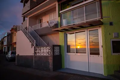a building with a sunset reflection in the window at Wave Shadows Beach House Oceanfront property - Bottom Floor in Paul do Mar