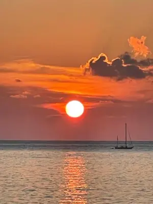 a sunset over the ocean with a boat in the water at Wave Shadows Beach House Oceanfront property - Bottom Floor in Paul do Mar