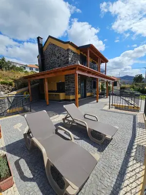 a patio with two lounge chairs and a building at Quinta das Rosas 6 Amaizing Seaview Trekking Beach in Estreito da Calheta
