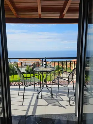 a table and chairs on a balcony with a view of the ocean at Quinta das Rosas 6 Amaizing Seaview Trekking Beach in Estreito da Calheta