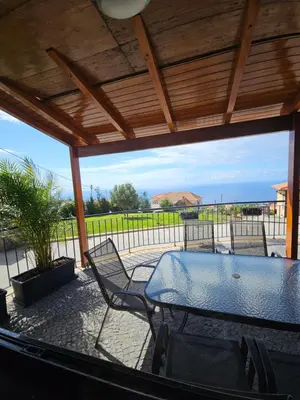a patio with a table and chairs and the ocean at Quinta das Rosas 6 Amaizing Seaview Trekking Beach in Estreito da Calheta