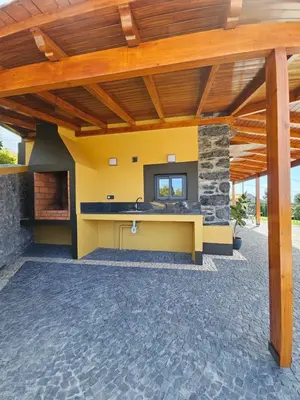 an outdoor kitchen with a fireplace in a house at Quinta das Rosas 6 Amaizing Seaview Trekking Beach in Estreito da Calheta