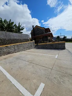 a building with a stone wall next to a parking lot at Quinta das Rosas 6 Amaizing Seaview Trekking Beach in Estreito da Calheta