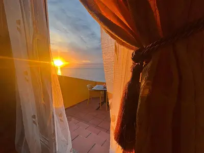 a table with a vase of flowers on a table with a sunset at Suite Bela Vigia 2 in Jardim do Mar