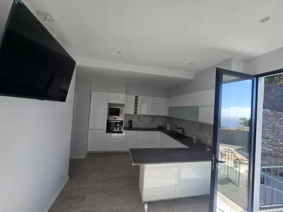 a kitchen with white cabinets and a flat screen tv at Ocean Paradise de Santa Luzia in Funchal