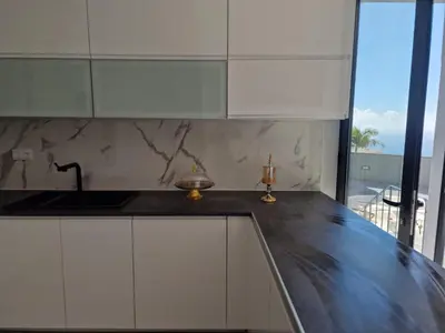 a kitchen with white cabinets and a black counter top at Ocean Paradise de Santa Luzia in Funchal