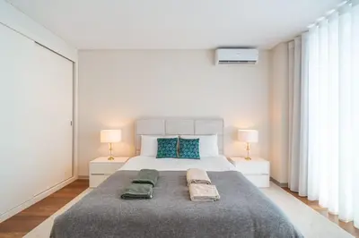 a white bedroom with a large bed with two lamps at La Vie Funchal - City Center & Free Park in Funchal
