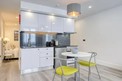 a kitchen with white cabinets and a table and chairs at BSE15 Apartments 1C, a Home in Madeira in Funchal