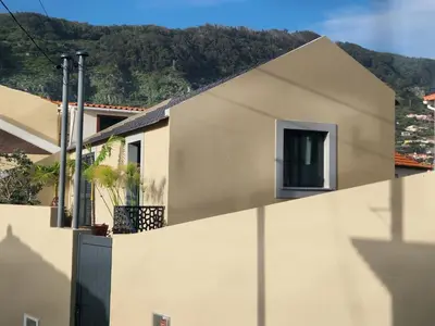 a white building with a window and a fence at Favinha Rooftop in Machico