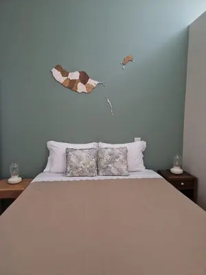 a bed with two pillows and a butterfly on the wall at Favinha Rooftop in Machico