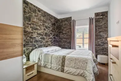 a bedroom with a bed and a brick wall at Casa da Avó Paraíso in Machico