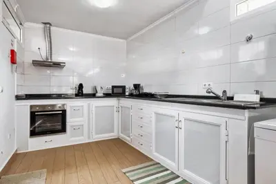a white kitchen with white cabinets and appliances at Casa da Avó Paraíso in Machico