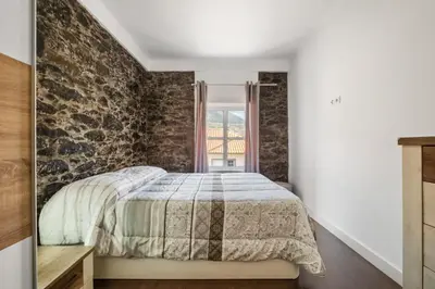 a bedroom with a stone accent wall and a bed at Casa da Avó Paraíso in Machico