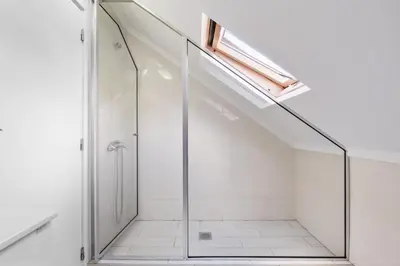 a glass shower in a white bathroom with a skylight at Casa da Avó Paraíso in Machico