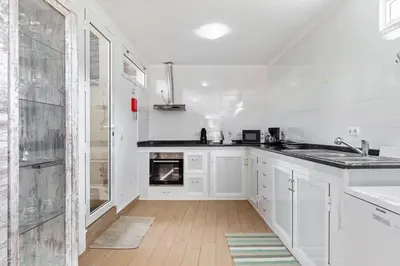 a white kitchen with a sink and a stove at Casa da Avó Paraíso in Machico