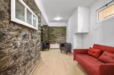 a living room with a red couch and a stone wall at Casa da Avó Paraíso in Machico