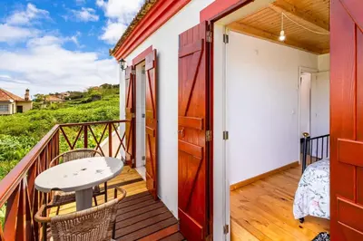 a balcony with a table and chairs and a table at Moniz Ocean Escape BBQ Near Porto Moniz Pools in Porto Moniz