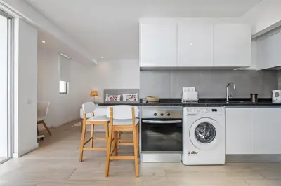 a kitchen with white appliances and a table and chairs at Step To The Sea 5, by Pausa Holiday Rentals in Funchal
