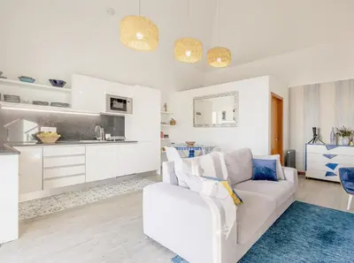 a white living room with a white couch and a kitchen at Villa Miradouro da Baleia (Heated Pool optional) in Ponta do Sol