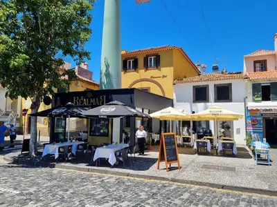 an outdoor cafe with tables and umbrellas on a street at Villa Nobrega by Holiday Rental Madeira in Funchal
