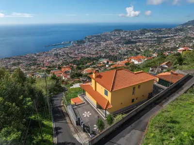 a yellow house on a hill overlooking the ocean at Villa Nobrega by Holiday Rental Madeira in Funchal