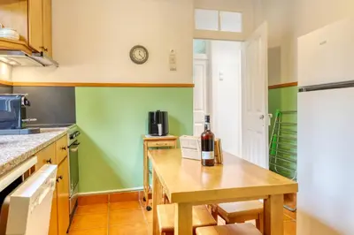 a kitchen with green walls and a table with a bottle of wine at Casa do Pinheiro I, a Home in Madeira in São Vicente