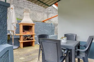 a patio with a table and chairs and a fireplace at Casa do Pinheiro I, a Home in Madeira in São Vicente