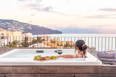 a woman sitting in a bath tub with a glass of wine at Ajuda I - Penthouse by Pausa Holiday Rentals in Funchal