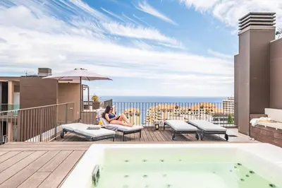 a woman sitting on a deck next to a hot tub at Ajuda I - Penthouse by Pausa Holiday Rentals in Funchal