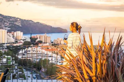 a woman standing on a balcony looking at a city at Ajuda I - Penthouse by Pausa Holiday Rentals in Funchal