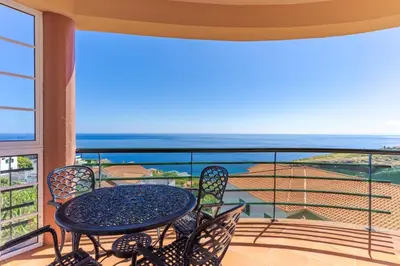 a table and chairs on a balcony with a view of the ocean at Alegria Apart. with Pool, by Pausa Holiday Rentals in Estreito da Calheta